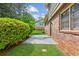 This backyard features a concrete patio, lush green lawn, brick facade, and manicured bushes at 3240 Corktree Trl, Stonecrest, GA 30038