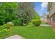 This backyard features a lush green lawn, mature trees, manicured bushes, and a wooden swing at 3240 Corktree Trl, Stonecrest, GA 30038