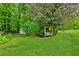 This backyard features a lush green lawn, mature trees, bushes, shed, and a wooden swing at 3240 Corktree Trl, Stonecrest, GA 30038