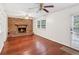 Bright living room featuring a brick fireplace, wood flooring, and a ceiling fan at 3240 Corktree Trl, Stonecrest, GA 30038
