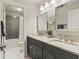 Well-lit bathroom featuring double sinks with granite countertops and a tub with a gray tiled wall at 1590 Johnson Ne Rd, Atlanta, GA 30306