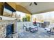 Cozy outdoor living area with stone fireplace, TV, grill and kitchen on a stone patio with seating at 2225 Independence Ln, Buford, GA 30519