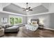 Spacious main bedroom with a tray ceiling, ceiling fan, and hardwood floors with a chaise lounge at 2740 Cezanne Ln, Cumming, GA 30041