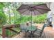 Outdoor wooden deck featuring dining table with an umbrella and view of the natural wooded back yard at 1812 Riverton Dr, Suwanee, GA 30024