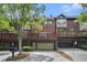 Townhome exterior with brick facade, wooden balconies, and garages, set against a green, leafy backdrop at 75 High Top Ln, Atlanta, GA 30328