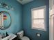 Bathroom with turquoise walls, small sink, toilet, and window at 1117 Balvaird Dr, Lawrenceville, GA 30045