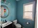 Bathroom with turquoise walls, small sink, toilet, and window at 1117 Balvaird Dr, Lawrenceville, GA 30045