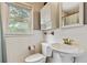 Bright bathroom featuring white tile, toilet, vanity, and a window providing natural light at 118 Greenwood St, Fairburn, GA 30213