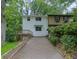 View of the home's exterior with a two-car driveway and stairs to front deck nestled in a wooded landscape at 2551 Park Se Rd, Smyrna, GA 30080