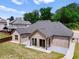 Brick home exterior with a concrete patio, lawn and view of the surrounding houses and tree line at 953 Auburn Rd, Dacula, GA 30019