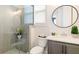 Modern bathroom with glass enclosed shower and round mirror above vanity at 1085 Celebration Dr, Roswell, GA 30076