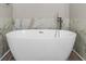 Close up of a standalone white tub with elegant fixtures and marble wall tile at 4524 Shumart Dr, Snellville, GA 30039