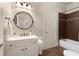 Bathroom featuring a vanity with marble countertop, round mirror, and a shower-tub combo with brown tile at 4674 Lakeway Pl, Alpharetta, GA 30005