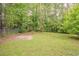 Large backyard with mature trees, a small concrete patio, and lush green grass for recreation and relaxation at 2212 Chestnut Log Loop, Lithia Springs, GA 30122