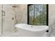 Modern bathroom featuring a luxurious soaking tub with brass fixtures and a large window view at 4978 Thornwood Nw Cv, Acworth, GA 30102