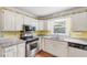 The kitchen includes white cabinets, granite countertops, stainless steel appliances and hardwood floors at 509 Orchards Walk, Stone Mountain, GA 30087