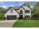Charming two-story brick home with manicured lawn and a black two-car garage against a cloudy sky at 230 Bluff Oak Dr, Roswell, GA 30076