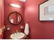 Hallway powder room featuring red walls, modern fixtures, an elegant light fixture and a round mirror at 230 Bluff Oak Dr, Roswell, GA 30076