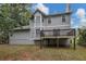 Backyard of a gray two story house with a deck and surrounded by trees at 565 Lake Joyce Ln, Fairburn, GA 30213