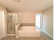 Well-lit bathroom features a soaking tub, glass-enclosed shower, and ceramic tile flooring at 2656 Gadsen Walk, Duluth, GA 30097