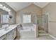 Well-lit bathroom featuring a soaking tub, a shower and a vanity sink with storage at 609 Grand Ashbury Ln, Buford, GA 30518