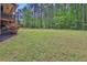 Spacious backyard with grass and flowers, trees in the background, and a partial view of the deck at 154 Carmen Ln, Dallas, GA 30157
