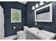 Bathroom with white fixtures, a blue wall, a window, and a modern sink and toilet at 154 Carmen Ln, Dallas, GA 30157