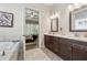 Bathroom with double sink, wooden cabinets, and a large tub at 3210 Steinbeck St, Cumming, GA 30041