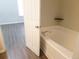 Bathroom featuring a soaking tub, wood-look flooring, and white painted door at 3216 Panthers Trce, Decatur, GA 30034