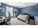 Blue bedroom with a bed, desk, ceiling fan and a large window with white curtains at 5015 Scuppernong Ct, Austell, GA 30106