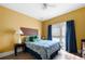 Bedroom with yellow walls, wood floors, a queen bed, and blue curtains over the window at 5015 Scuppernong Ct, Austell, GA 30106