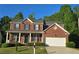 Charming two-story brick home featuring a covered front porch and a two car garage in a suburban neighborhood at 7491 Hilltop Way, Atlanta, GA 30349