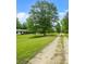 View of the yard of the home, with lush green grass and a dirt driveway leading up to the house at 415 Gray Rd, Carrollton, GA 30116