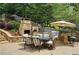 Backyard with stone fireplace, outdoor kitchen, dining area, and lush landscaping, creating an inviting outdoor space at 1657 Millhouse Lndg, Marietta, GA 30066