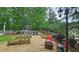 Large backyard with garden beds, fire pit, seating, and mature trees, creating a peaceful outdoor space at 1657 Millhouse Lndg, Marietta, GA 30066