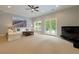 Spacious living room with plush carpet, a ceiling fan, large doors, and an entertainment center at 5045 Huntwood Way, Roswell, GA 30075
