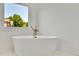 Bright bathroom showcasing a modern standalone tub with a picturesque window view at 5753 Brendlynn Dr, Suwanee, GA 30024
