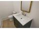 Chic powder room with a decorative mirror and a green vanity with marble countertop and gold hardware at 5753 Brendlynn Dr, Suwanee, GA 30024