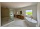 This bathroom features a soaking tub, a glass shower, and a large window with a view at 5753 Brendlynn Dr, Suwanee, GA 30024