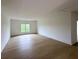 Spacious room with hardwood floors, white walls, and a bright window at 5753 Brendlynn Dr, Suwanee, GA 30024