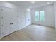 Well-lit bedroom showcasing hardwood floors, double closets, and a window overlooking greenery at 5753 Brendlynn Dr, Suwanee, GA 30024