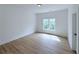 Bright bedroom with light wood floors, white walls, and a large window at 5753 Brendlynn Dr, Suwanee, GA 30024