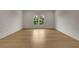 Bright bedroom features hardwood floors, white walls, and a window with green outdoor view at 5753 Brendlynn Dr, Suwanee, GA 30024