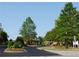 Community entrance with lush landscaping, trees, flowers, and a gate house under a blue sky at 5753 Brendlynn Dr, Suwanee, GA 30024