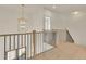 Modern hallway with black metal railing, hardwood steps, and a decorative hanging light fixture at 5753 Brendlynn Dr, Suwanee, GA 30024