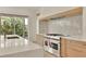 Bright kitchen with stainless steel stove, marble countertops, and a large window overlooking a green landscape at 5753 Brendlynn Dr, Suwanee, GA 30024