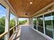 Outdoor patio with wood ceiling, brick wall, ceiling fan, wood railings, and large glass sliding doors at 5753 Brendlynn Dr, Suwanee, GA 30024