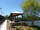 Community Tennis courts with shaded pergola, stone wall, and lush landscaping at 5753 Brendlynn Dr, Suwanee, GA 30024