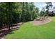 Beautiful backyard with a gentle slope, mature trees, and a glimpse of the deck, creating a serene outdoor space at 225 Blueberry Rdg, Milton, GA 30075