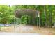 Long metal carport with gravel parking and trees in the background at 320 Williamsburg Cir, Mcdonough, GA 30253